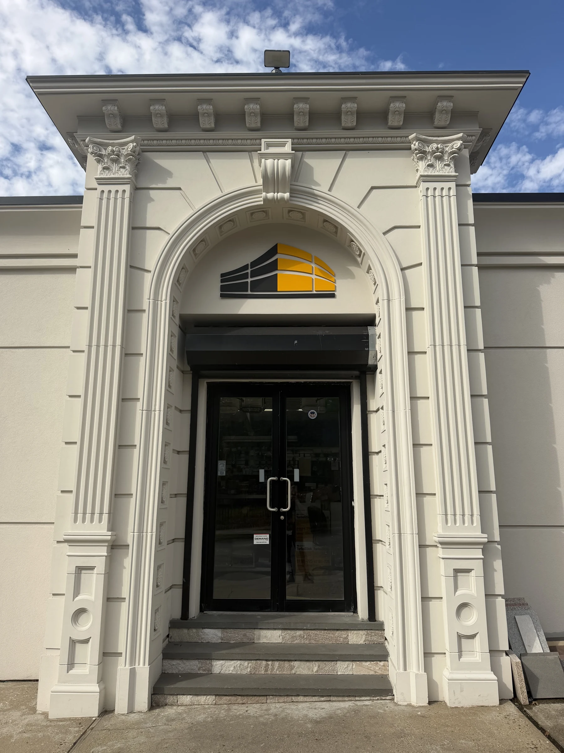 Entrada de Hempstead Stucco Supply con columnas decorativas y el logotipo de HSS
